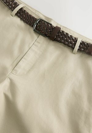 Shorts in cotone beige con una texture liscia, caratterizzati da una cintura in pelle marrone intrecciata e una fibbia metallica argentata.