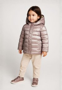 Giacca a vento metallizzata di un rosa chiaro, con cappuccio e design trapuntato. Abbinata a pantaloni beige e sneakers con cinturini marroni.