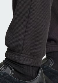 Sorte strukturerede joggerbukser med ribbet manchet, parret med sorte sneakers med en glat læderoverdel og bløde suede-detaljer.