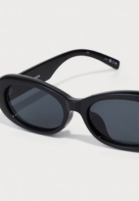Musthave tumed prillid ovaalsete, suurte läätsedega. L�äbipaistev plastikraam, tumedat tooni läätsed ja kõverad osad. Minimalistlik disain.