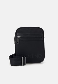 Černá nylonová crossbody taška s přední kapsou na zip, nastavitelným popruhem a minimalistickým designem. Hladká textura a obdélníkový tvar.