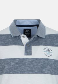 Polo skjorte i blå og hvide striber med knapkrave, tekstureret stof og et logo-patch på venstre side.