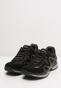 Schwarze Sportschuhe mit einem atmungsaktiven Mesh-Obermaterial, reflektierenden Akzenten, einer gepolsterten Sohle und elastischen Schnürsenkeln für einen sicheren Sitz.