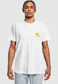 Hvid bomulds t-shirt med et lille gult bananmotiv på venstre bryst, korte ærmer og rund hals.