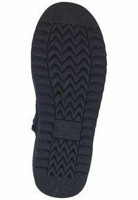 Suela de zapato de goma negra con un patrón de tracción en zigzag, con un tacón plano y una marca de logotipo cerca del centro.