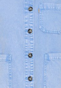 Hellblaues Jeanshemd mit Knopfleiste, sechs schwarzen Knöpfen und einer Brusttasche auf der linken Seite mit gestickter Umrandung. Glatte Textur.