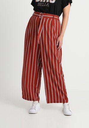 Wide-legged, high-waisted pants in a red fabric with white vertical stripes. Features a matching belt at the waist and mock pockets.