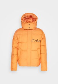 Pomarańczowa kurtka puchowa z wysokim kołnierzem, zatrzaskami, przednim zamkiem błyskawicznym oraz naszywaną kieszenią z logo „Calvin”. Gładka tekstura, pikowany wzór.