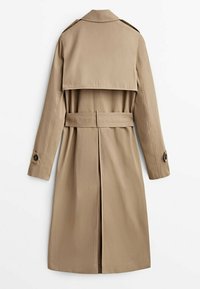 Trench-coat kaki à double boutonnage, grand col, épaulettes, taille cintrée par une ceinture, et une fente à l'arrière pour faciliter les mouvements.