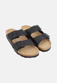 Black sandals with two adjustable buckles, cork footbed, tan inner lining, and textured black rubber sole.