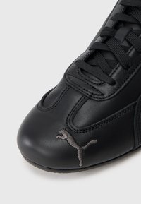 Pantof negre din piele sintetică, cu vârful rotund, având șireturi negre și un logo brodat gri pe lateral. Textură netedă și design minimalist.