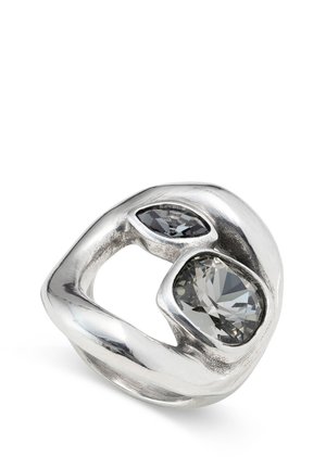 Bague en argent présentant une forme organique avec deux pierres précieuses multi-facettes : l'une grise et l'autre transparente, serties dans un métal poli.