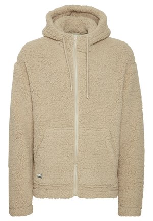 Beige fleece hoodie with a zip front, textured fabric, dual front pockets, and a drawstring hood. Features a small logo on the lower left side.