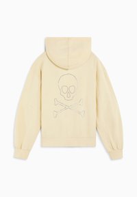 Sudadera amarilla con un diseño de calavera y tibias en plata con tachuelas en la parte posterior. Cuenta con una capucha ajustable y puños acanalados.