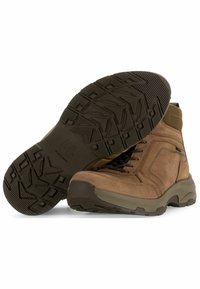 Botas de senderismo de ante marrón con suela de goma, que presentan patrones de agarre texturizados y cordones con ojales. Diseño de corte medio para soporte en el tobillo.
