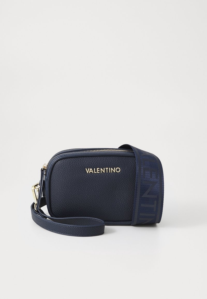 Borsa a tracolla in pelle blu navy con finitura testurizzata, logo dorato e tracolla regolabile con un accentuato motivo. Chiusura con zip nella parte superiore.