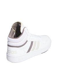 Sneaker alta bianche con dettagli beige e grigi, caratterizzate da tre strisce e un retro testurizzato. Fodera interna morbida, suola piatta in gomma.