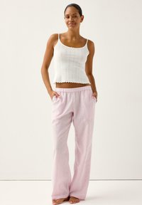 Top bianco a coste con orlo smerlato abbinato a pantaloni larghi a righe rosa chiaro, con vita elastica e vestibilità comoda.