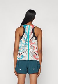 Lätt, ärmlös atletisk tank med ett meshdesign, featuring blå och röda abstrakta mönster på en vit bakgrund, tillsammans med turkosa short. 