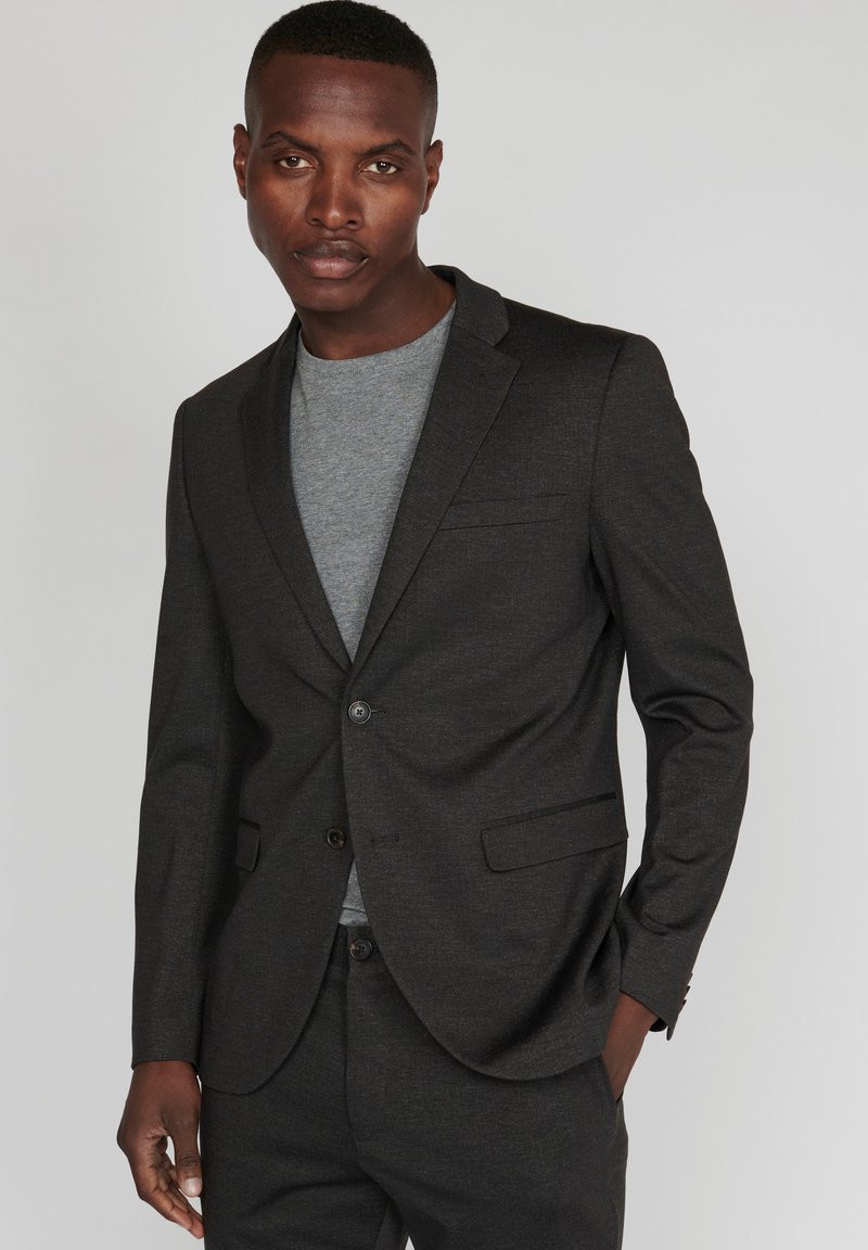 Tumed hall blazer slim fit'i, ühe nupuga sulgemisega, soonikute krae ja kahe eesoleva taskuga. Kantakse heledast hallist T-särgist üle.