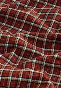 Tissu à carreaux rouge et noir avec une texture agréable, présentant un motif de grille avec des lignes blanches, jaunes et orange entrelacées.