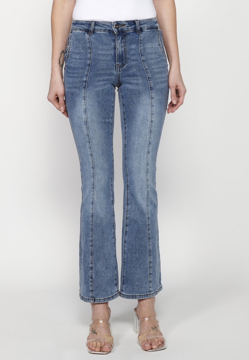 Uppfläkt blå denimjeans har hög midja med en slät yta, synliga stygn och en lätt blekt tvätt för en avslappnad look.