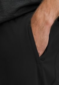 Schwarze Sportshorts mit Seitentasche, aus einem glatten, leichten Material und mit einem verdeckten Reißverschluss für sichere Aufbewahrung.
