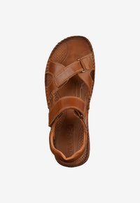 Brown leather sandal with adjustable straps, textured insole, and patterned sole. Features buckle hardware and perforated detailing for breathability.