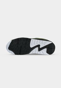 Η σόλα ενός αθλητικού παπουτσιού Nike με μαύρο και λευκό καουτσούκ, με τετράγωνα και γραμμικά σχέδια για πρόσφυση και στήριξη.
