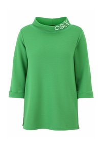 Grünes, geripptes Strickoberteil mit einem Trichterkragen und Dreiviertelärmeln, das ein weißes „BE COOL“-Logodetail am Kragen aufweist.