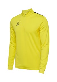 Jasnożółty sportowy pulower z długim rękawem, z suwakiem do ćwiartki, czarne logo hummel na piersi i czarne paski na ramionach.