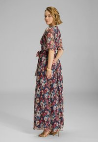 Robe maxi en tissu transparent avec un motif floral abstrait multicolore. Liaison à la taille, avec des manches courtes et une coupe fluide.