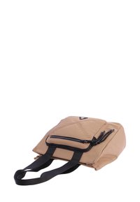 Bolso rectangular beige con bolsillo con cremallera negra, asas negras y un pequeño logo triangular en la parte frontal, sobre un fondo blanco.