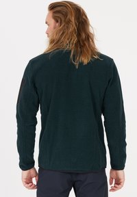Mörkgrön fleecejacka med en strukturerad yta, med en svart armb�ågsplatta, långa ärmar och en avslappnad passform.