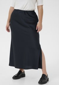 Gonna maxi blu navy realizzata in tessuto morbido, con vita elasticizzata e uno spacco laterale, abbinata a mocassini neri.