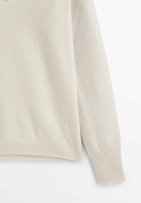 Pull à manches longues de couleur crème avec poignets et ourlet côtelés, présenté sur fond blanc.