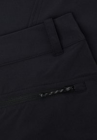 Pantaloni negri cu un design cu față plată, buzunar cu fermoar și accente din plasă, având o textură netedă. Detaliile taliei sunt bine definite.