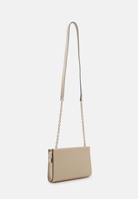 Beige křížová taška vyrobená z hladkého materiálu, s řetízkovým popruhem, elegantním designem a minimalistickými akcenty.