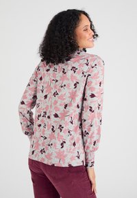 Grijs top met lange mouwen en een roze bloemenpatroon, gemaakt van zachte stof en met een relaxte pasvorm. Accenten zijn onder andere geplooide manchetten en een halslijn.