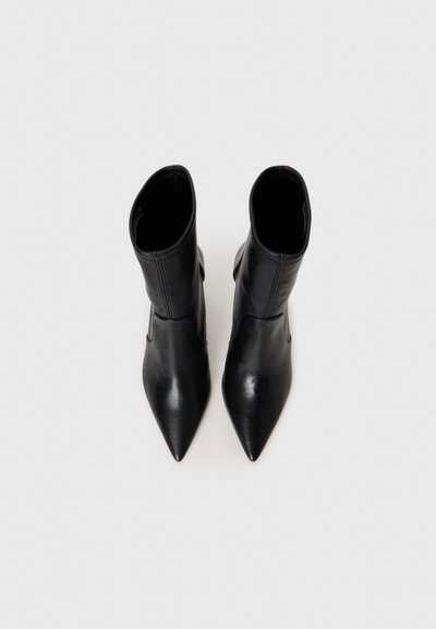 Zwarte leren enkellaarsjes met een spitse neus en een slanke hak. Het ontwerp heeft een elegantere uitstraling en minimale stikseldetails.