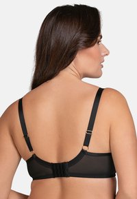 Sujetador negro con tela de malla transparente, tirantes ajustables, piezas metálicas doradas y cierre de gancho en la parte posterior. Diseño simple y funcional.