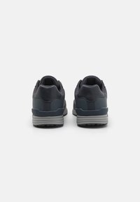 Zapatillas deportivas de color azul marino con una parte superior texturizada, mediasuela acolchada y suela de goma. Cuenta con un collar acolchado y acentos en gris que contrastan.