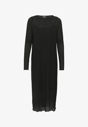 Musta neulemekko, jossa on pitkät hihat, avoin kudontakuvio, pyöreä kaula-auko ja suora leikkaus, joka ulottuu pohkeisiin.