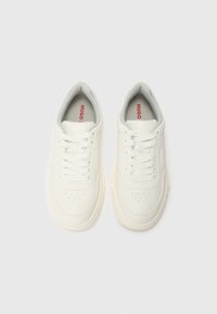 Adidași albi cu un tipar din piele netedă, vârful rotund, design cu șireturi și branding roșu "HUGO" pe limbă. Captuseală moale de culoare gri.