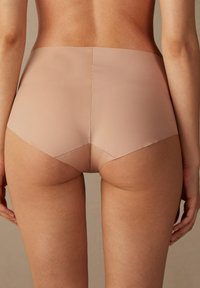 Hochtaillierte, nahtlose beigen Unterwäsche mit glatter Textur; verfügt über einen mittelhohen Beinausschnitt und minimale Nähte für ein elegantes Erscheinungsbild.