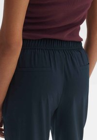 Marineblauwe broek met elastische taille en twee achterzakken. Gemaakt van een soepele, lichte stof met een slank, aansluitend ontwerp.