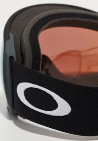 Lunettes de ski avec une sangle élastique noire portant un logo blanc, un verre orange et un revêtement intérieur en mousse noire douce pour le confort.