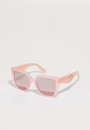 Óculos de sol rosa, em formato quadrado, com lentes degradê, feitos de material transparente. Apresenta detalhes em dourado nas laterais e uma textura suave.