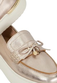 Metallic gold leather loafers with a rounded toe, decorative laces, and a white rubber sole. Features subtle stitching and gold accents.
