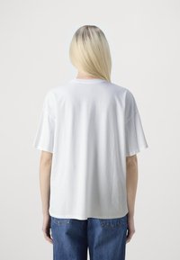 Camiseta de algodón blanca con un corte relajado, mangas cortas y cuello redondo. La vista trasera muestra una textura suave y un diseño simple.